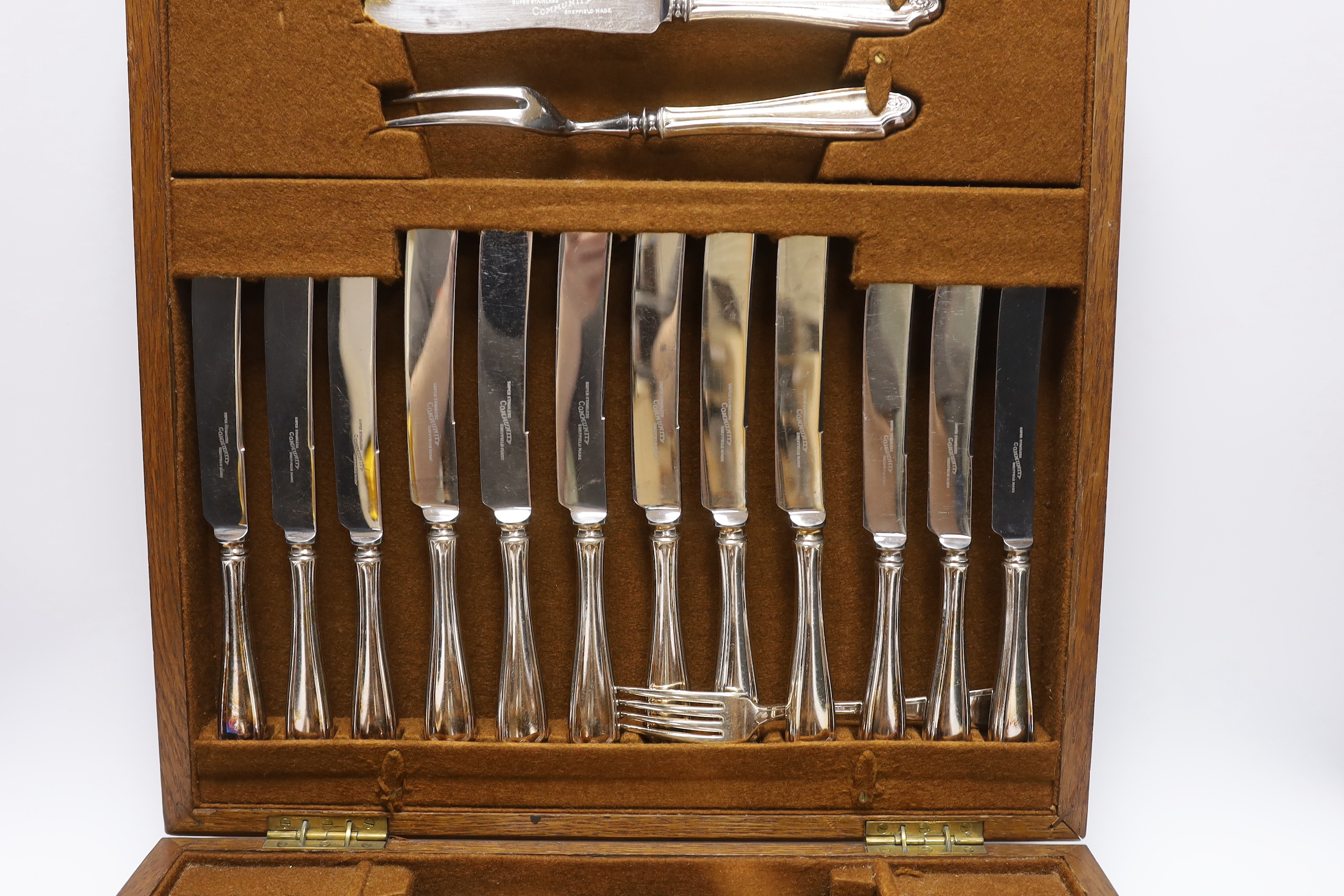 An oak cased canteen containing Sheffield ‘Super stainless’ flatware and a pair of plated candelabra, 46cm